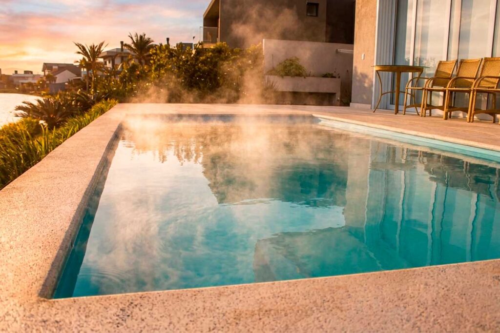 Piscina Glass aquecida com vapor sobre a água, demonstrando o conforto térmico do aquecimento solar