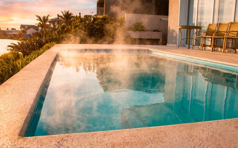 Piscina Glass aquecida com vapor sobre a água, demonstrando o conforto térmico do aquecimento solar